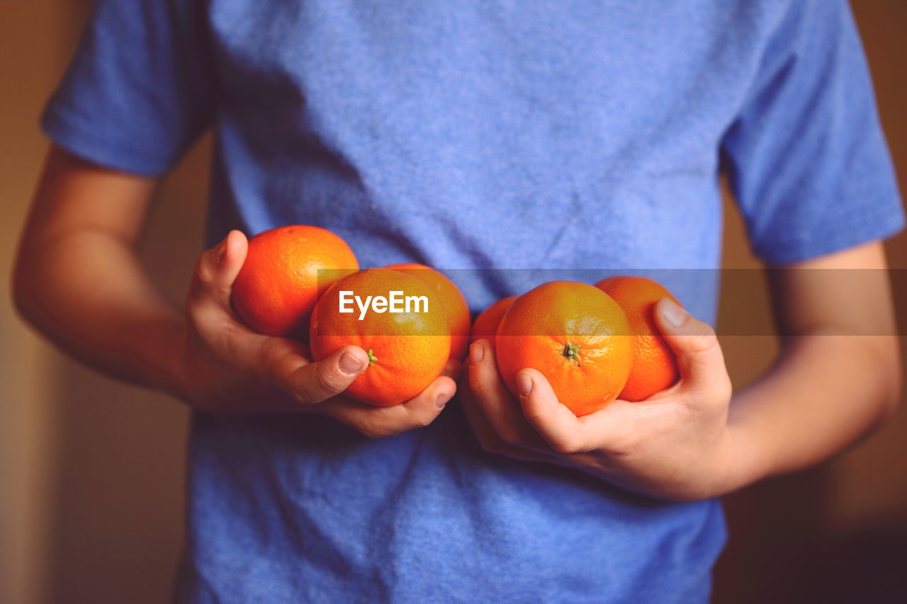 Midsection of man holding oranges