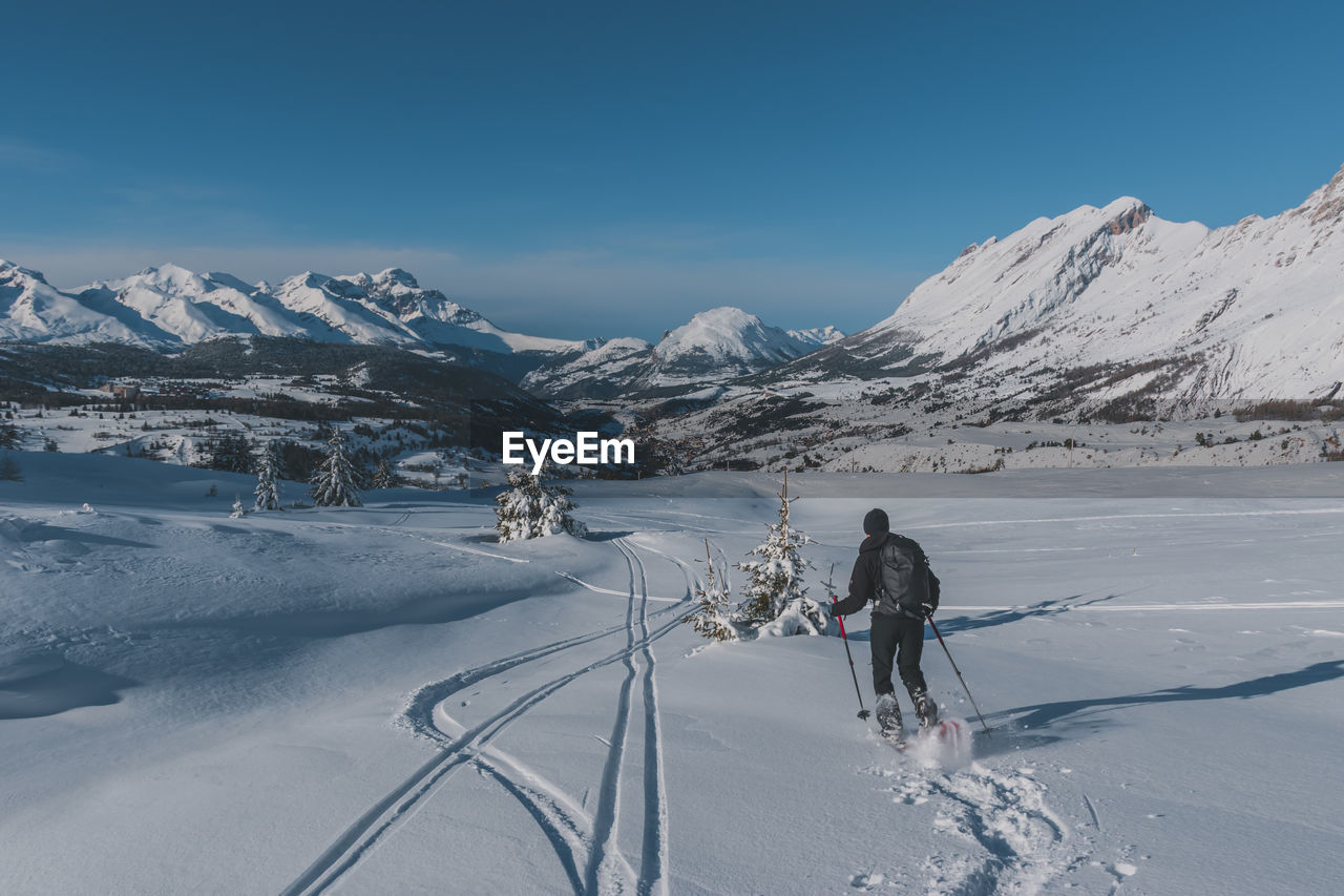 An unrecognizable male hiker wearing snowshoes running in the french alps on a cold winter day