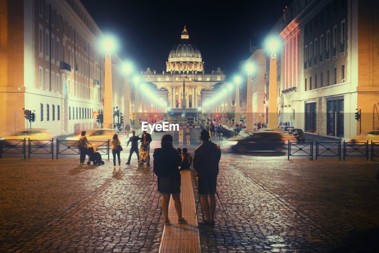 PEOPLE AT ILLUMINATED CITY AT NIGHT