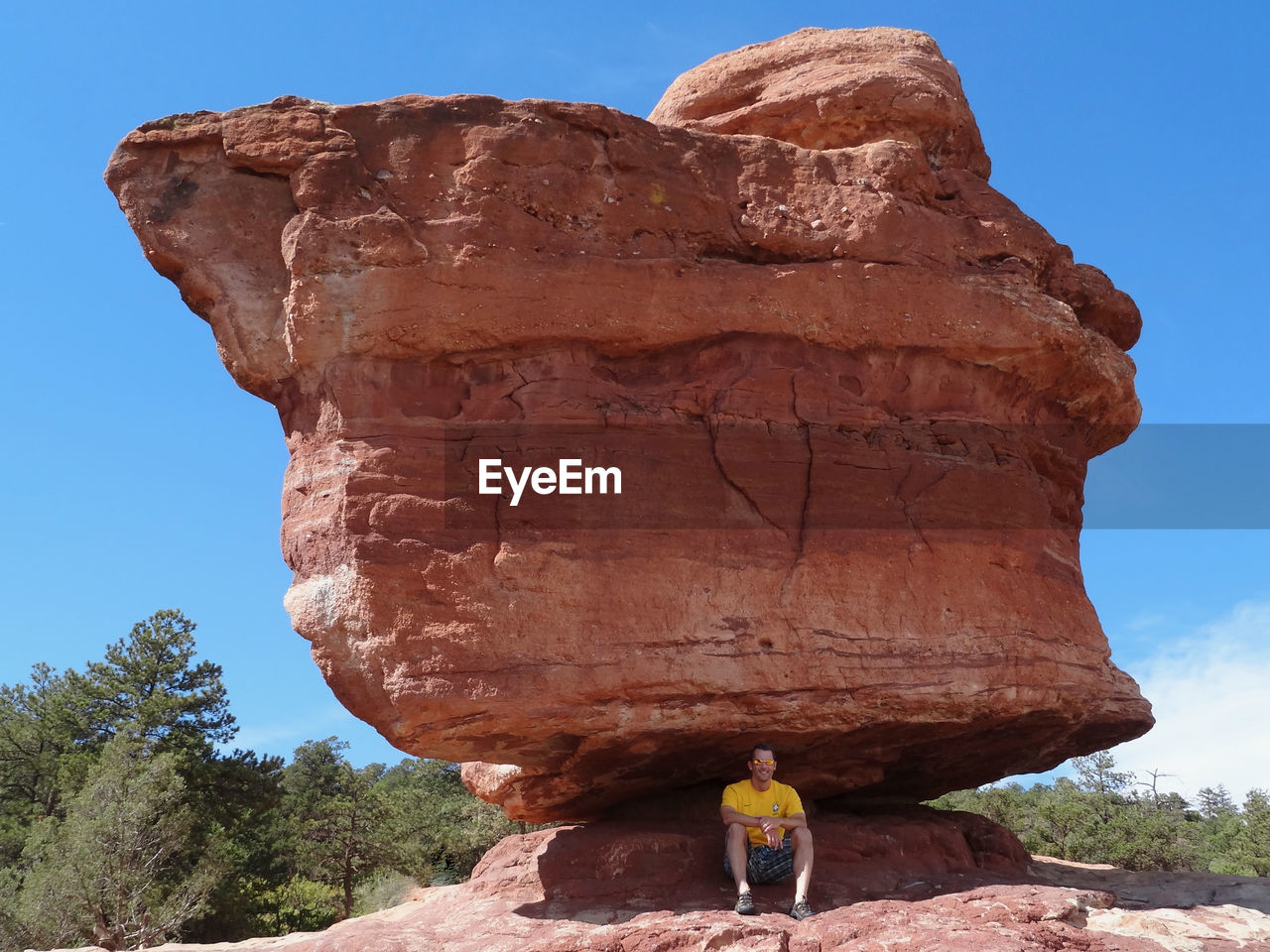 Man sitting under balanced rock at garden of the gods park in colorado springs