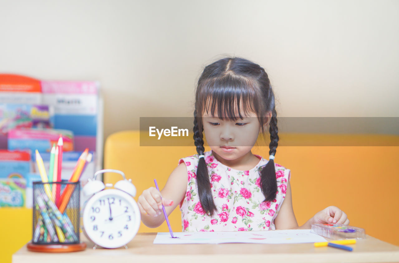 Close-up of cute girl sitting by table