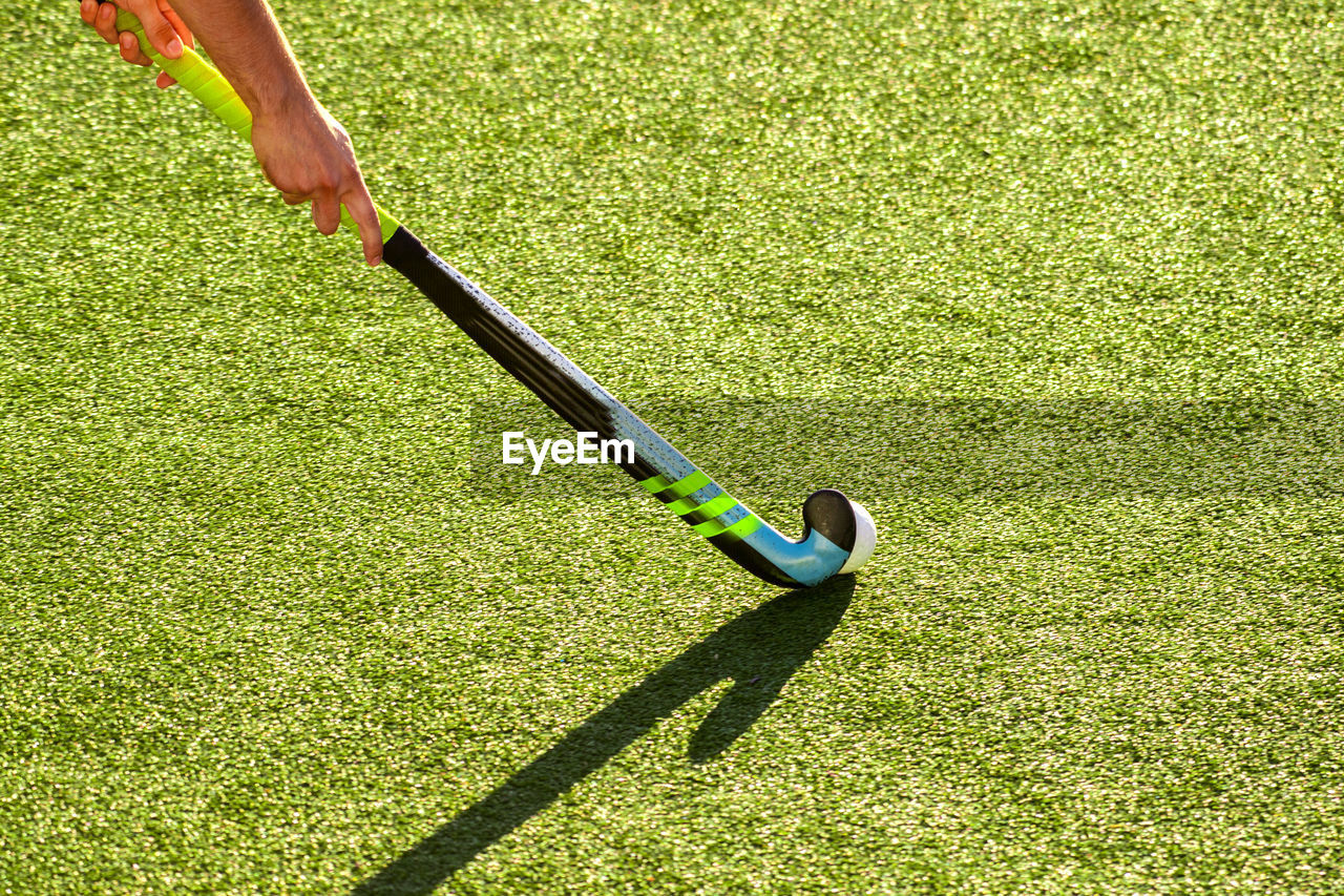 Cropped image of player playing hockey on field during sunny day