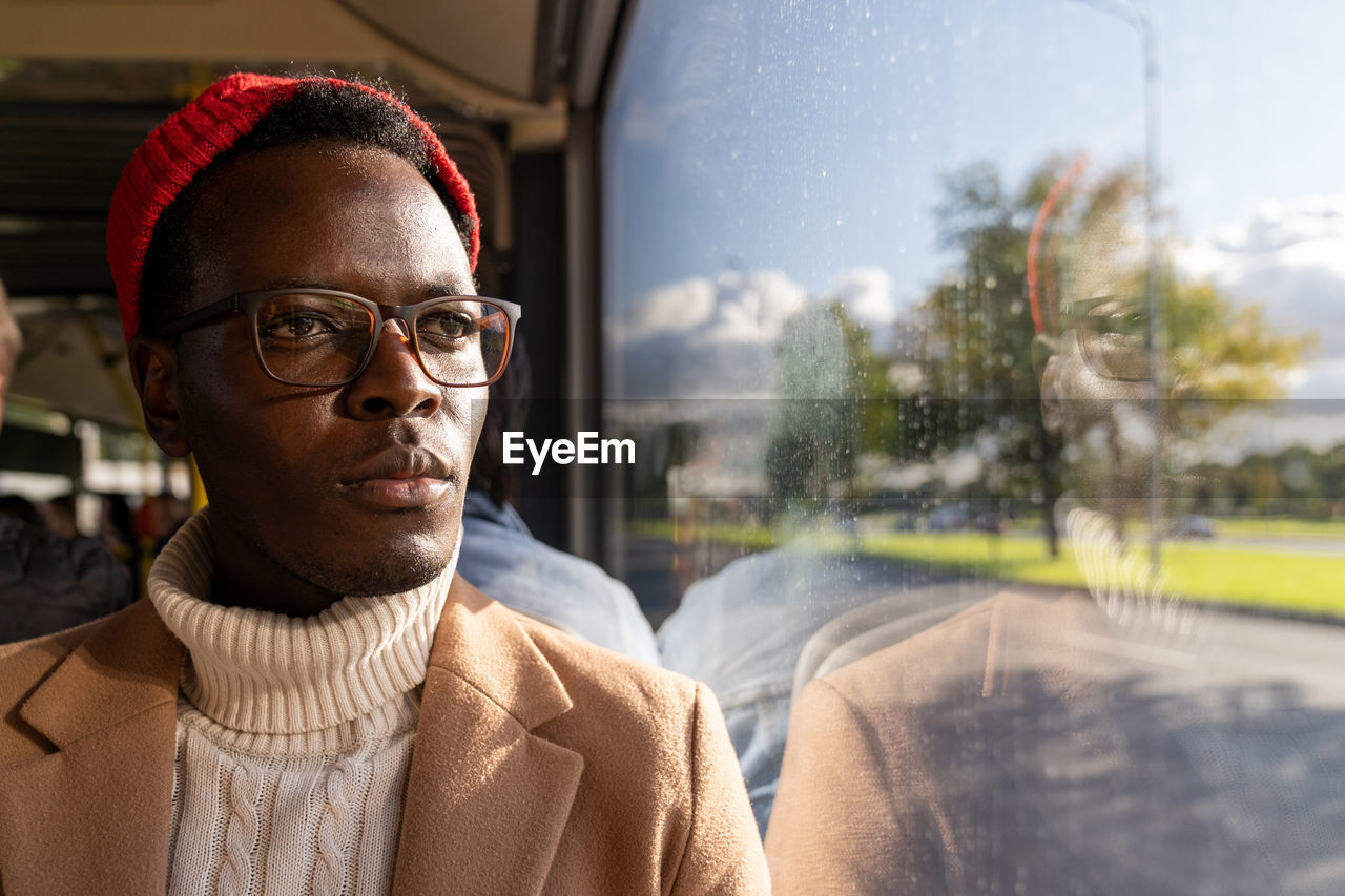 African american traveler man wearing glasses, looking at window, traveling by public transportation