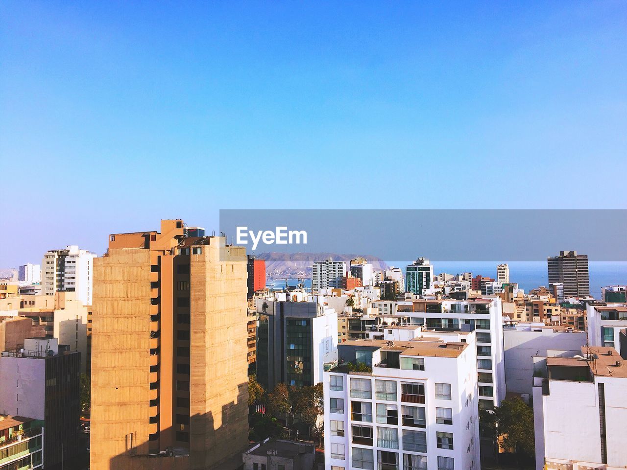 Buildings in city against clear blue sky