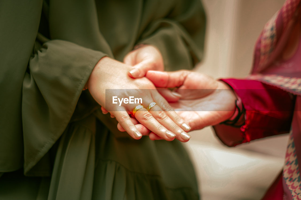 Midsection of couple holding hands, engagement day