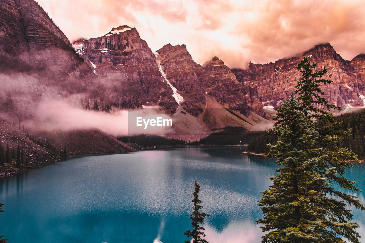 Scenic view of lake by mountains against sky during sunset