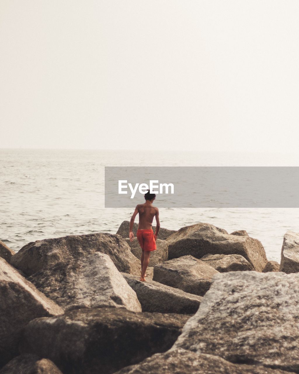 REAR VIEW OF WOMAN LOOKING AT SEA SHORE