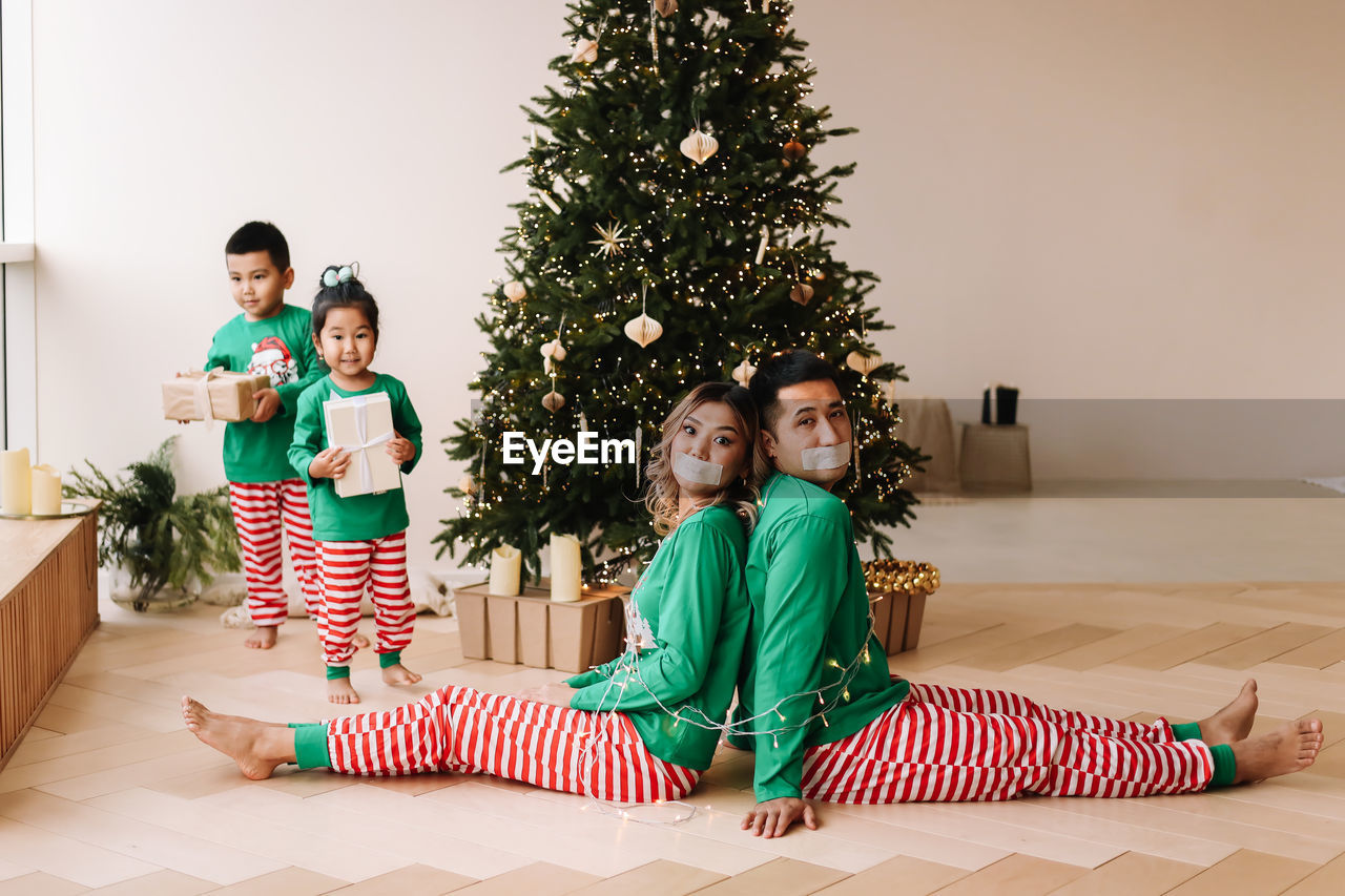 Children tied their parents with rope.  family is having fun and playing christmas holiday at home