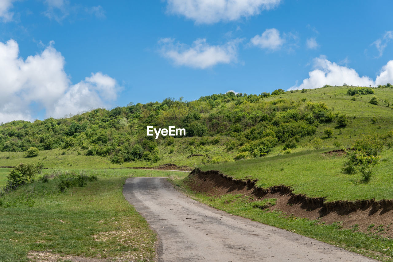 Road amidst green landscape against sky