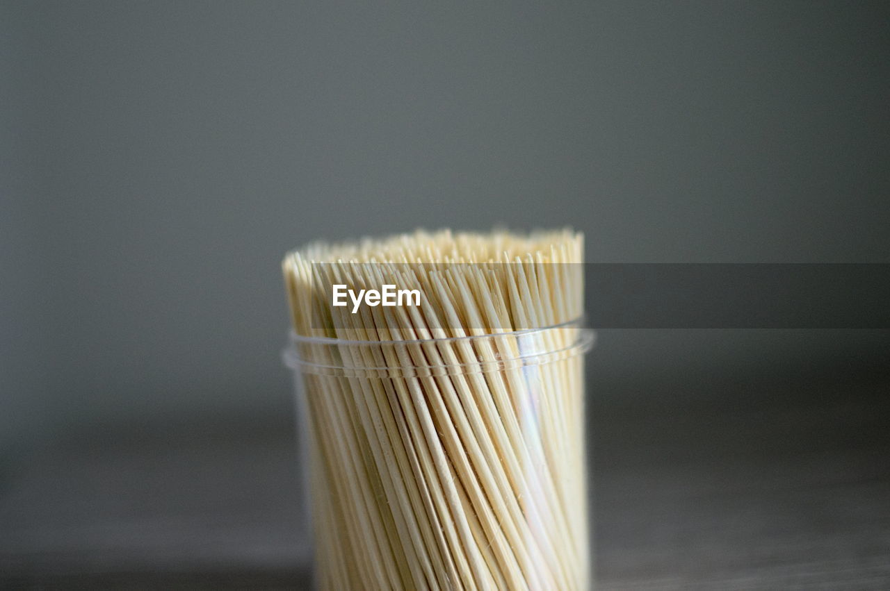 Close-up of toothpicks in glass container on table