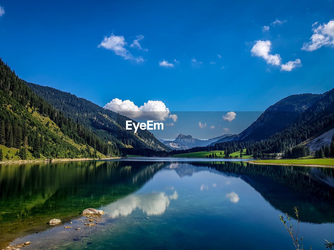 Scenic view of lake and mountains against blue sky