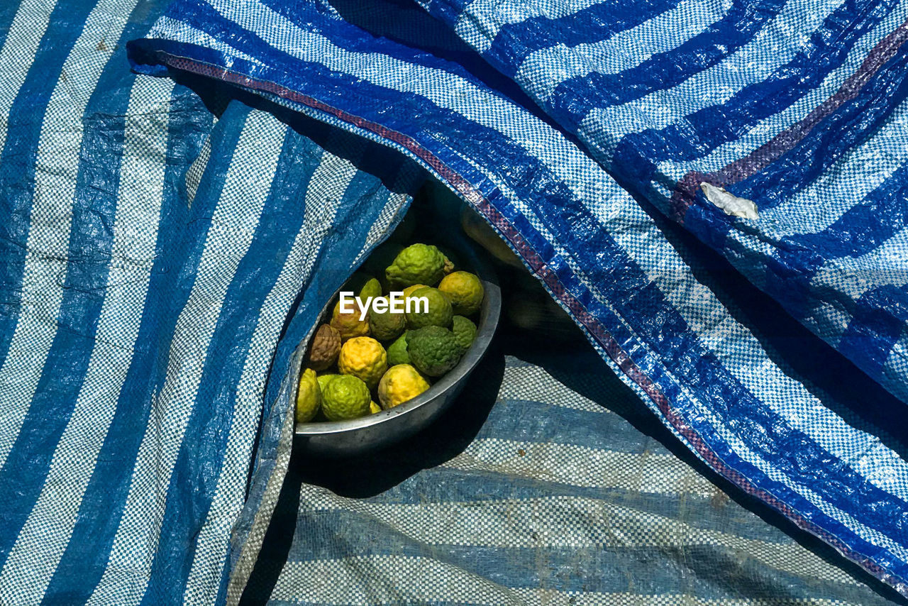 HIGH ANGLE VIEW OF FRUITS IN CONTAINER ON GREEN TABLE