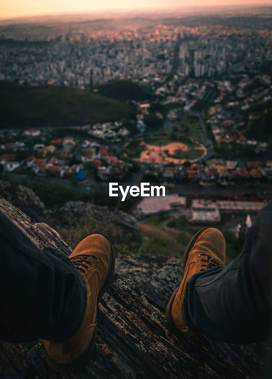 Low section of person on wood against cityscape and sky