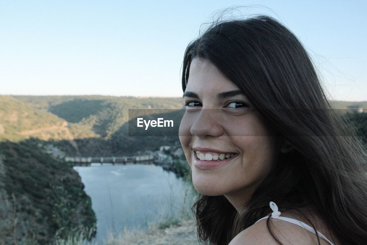 Portrait of happy young woman against mountains and clear sky at miranda do douro