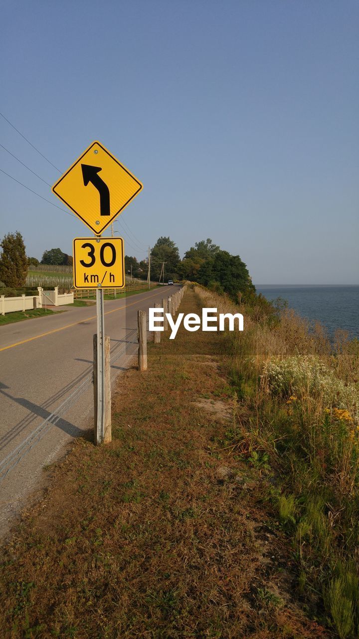 ROAD SIGN ON FIELD AGAINST SKY