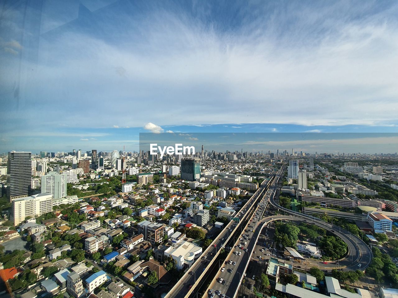 HIGH ANGLE VIEW OF ROAD BY BUILDINGS AGAINST SKY