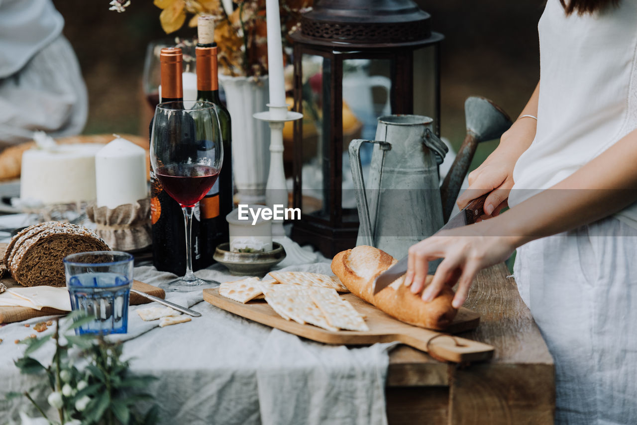 Midsection of woman cutting bread on table