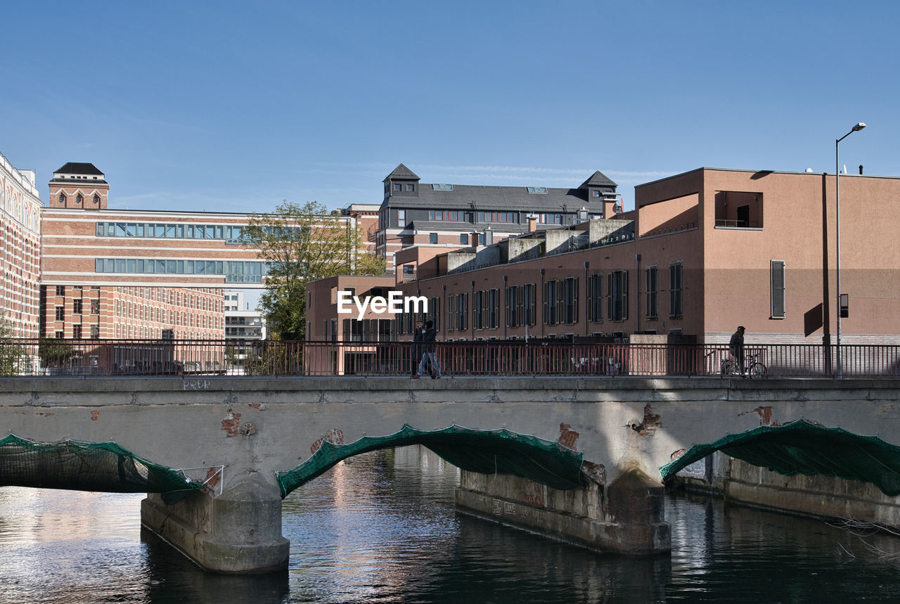 BUILDINGS BY RIVER AGAINST CLEAR BLUE SKY