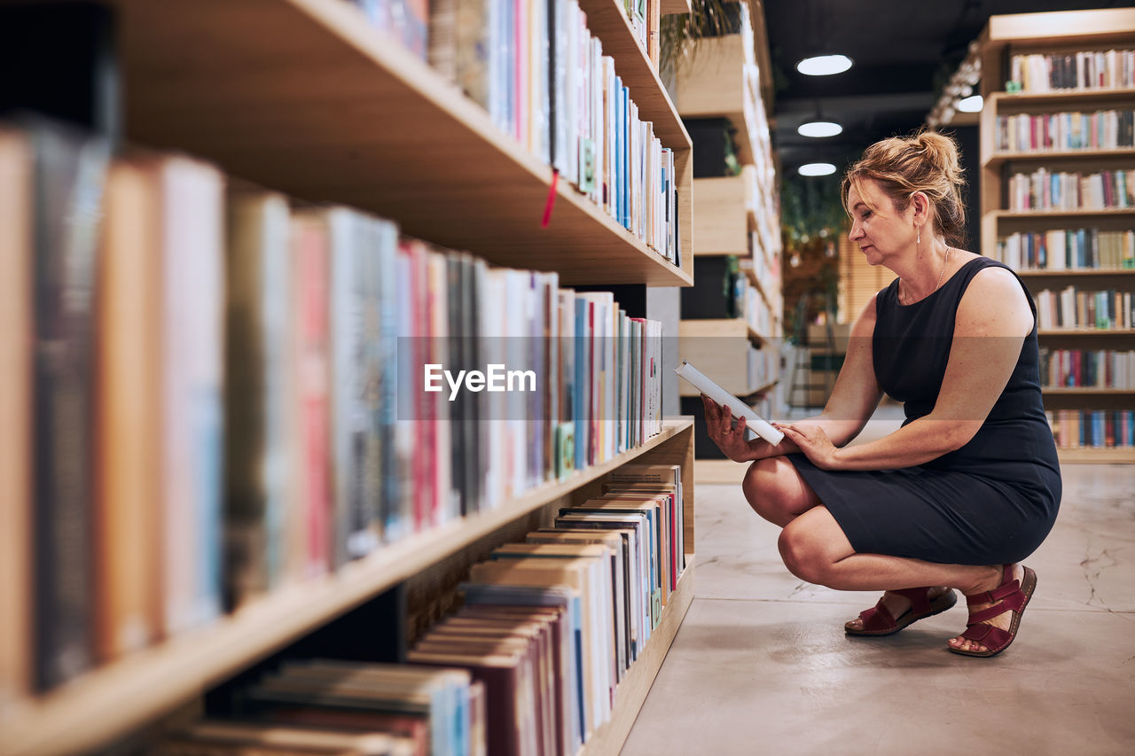 Woman reading book in public library. reading and learning. searching for literature. choosing book