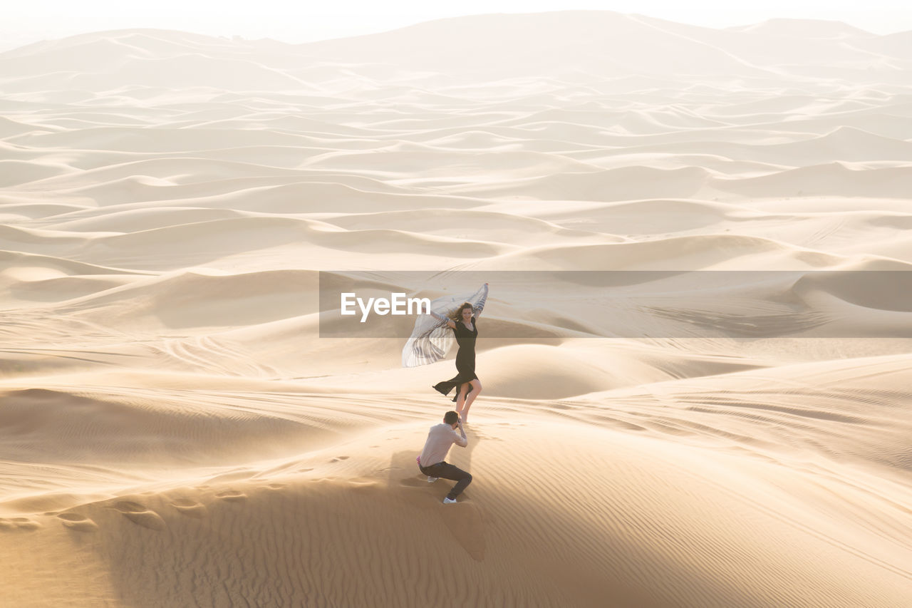 High angle view of man photographing woman at desert
