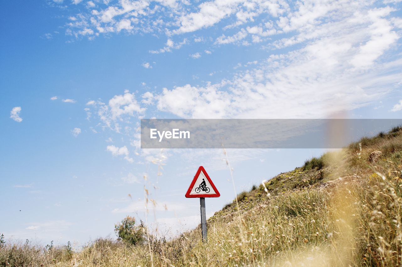 Road sign on field against sky