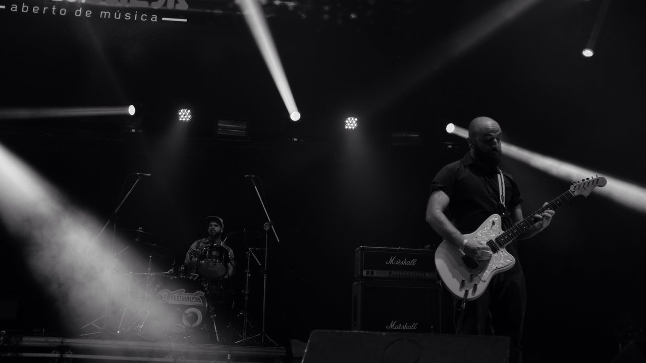 PERSON PLAYING GUITAR IN MUSIC CONCERT