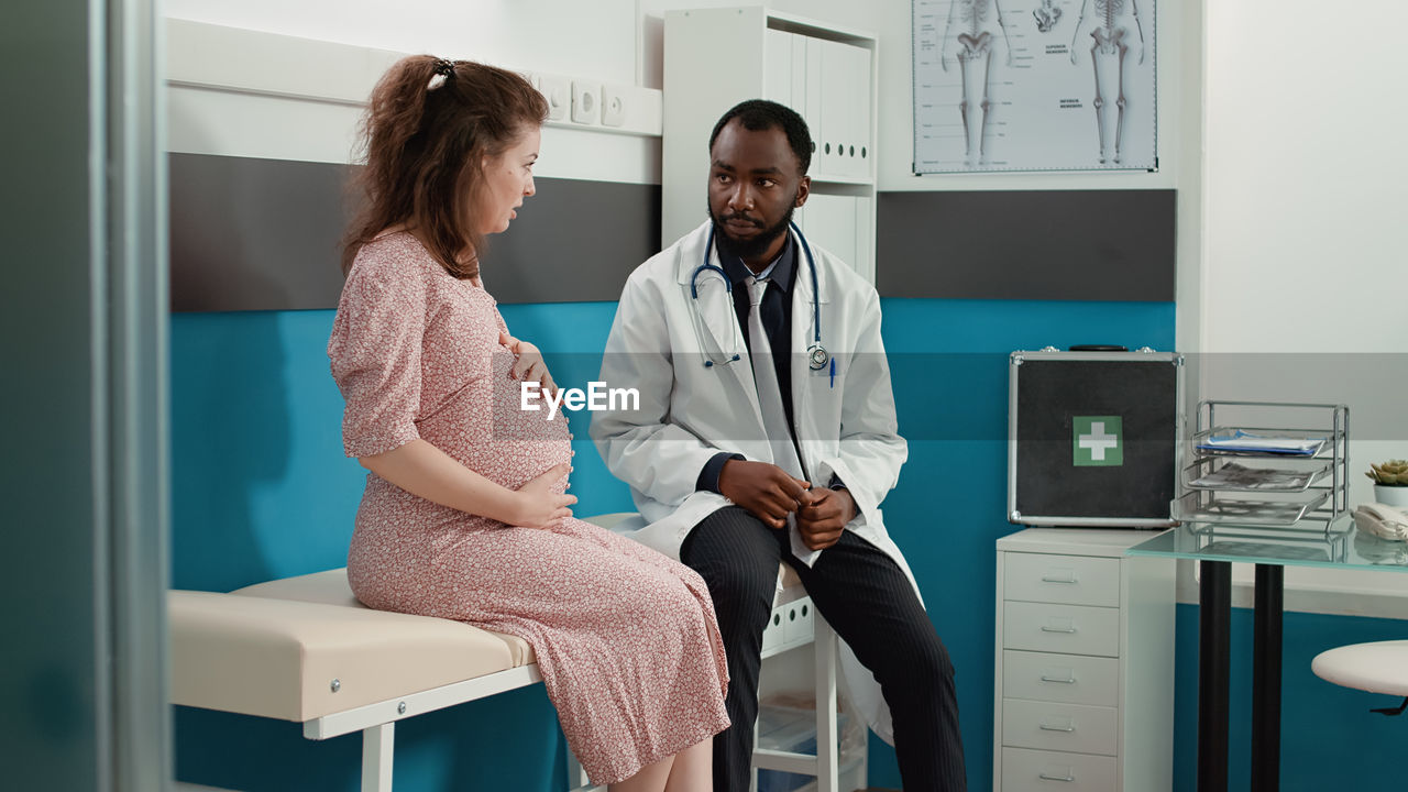 Young woman using mobile phone while standing in clinic