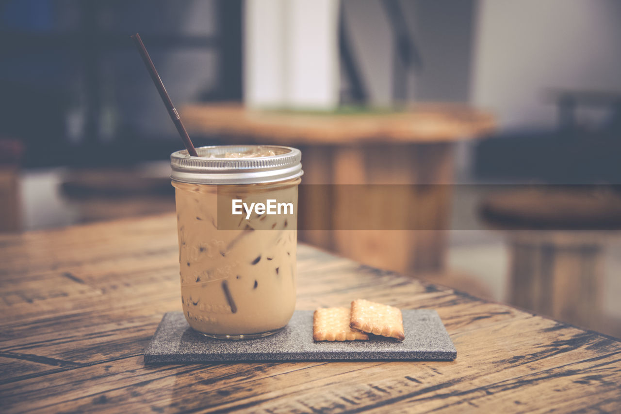 Iced coffee and cracker served on wooden table