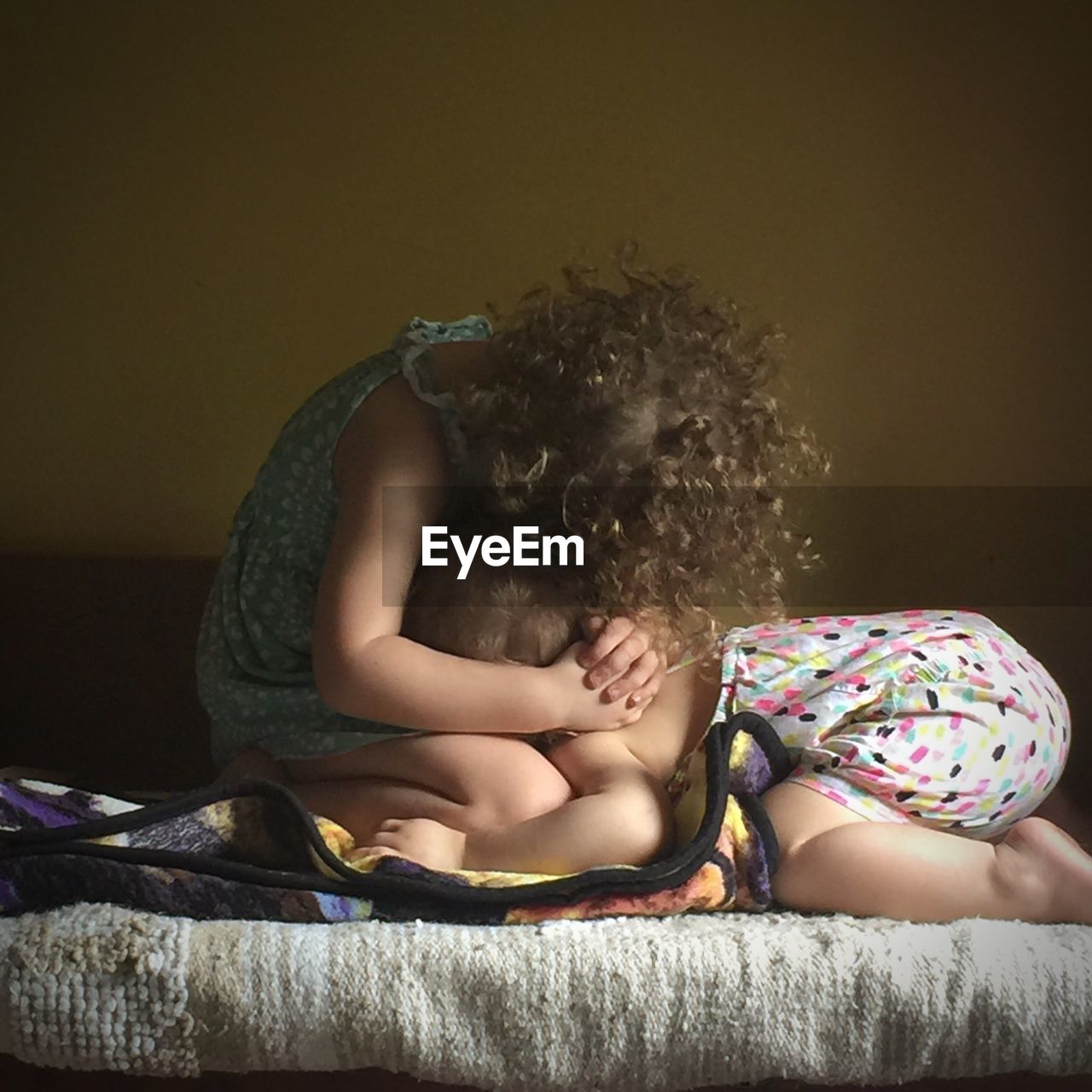 Siblings sitting on bed at home