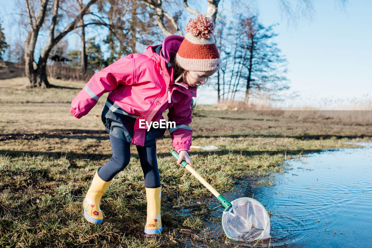 Young girl playing with a fishing net in the sea on a sunny winter day