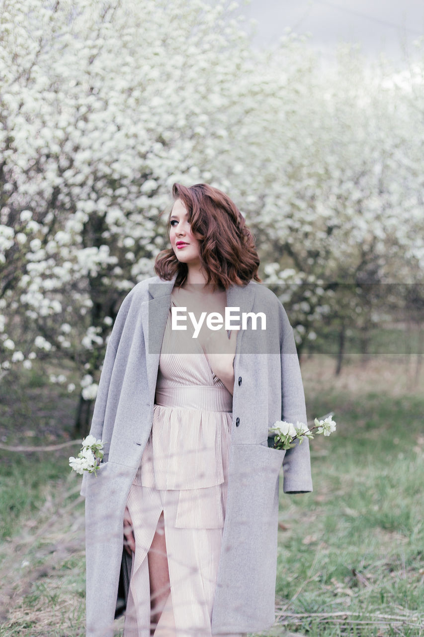 Beautiful girl in a dress walking in a blooming garden