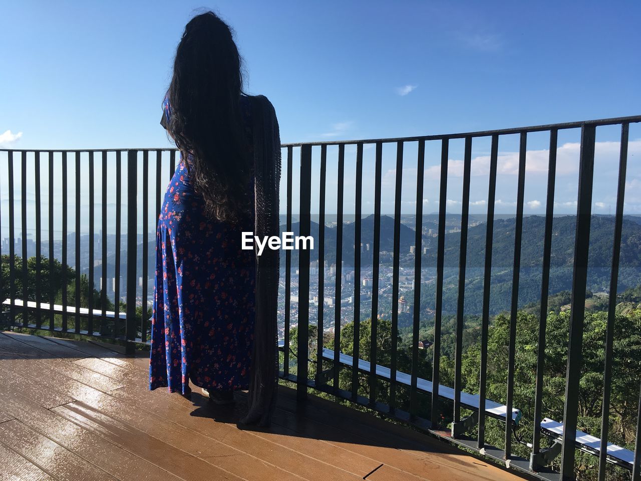 Rear view of woman standing by railing against sky