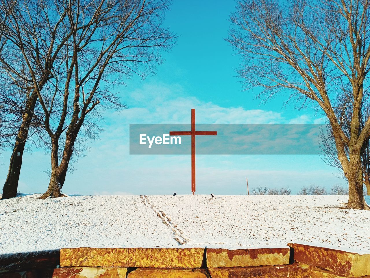 CROSS ON FIELD AGAINST SKY