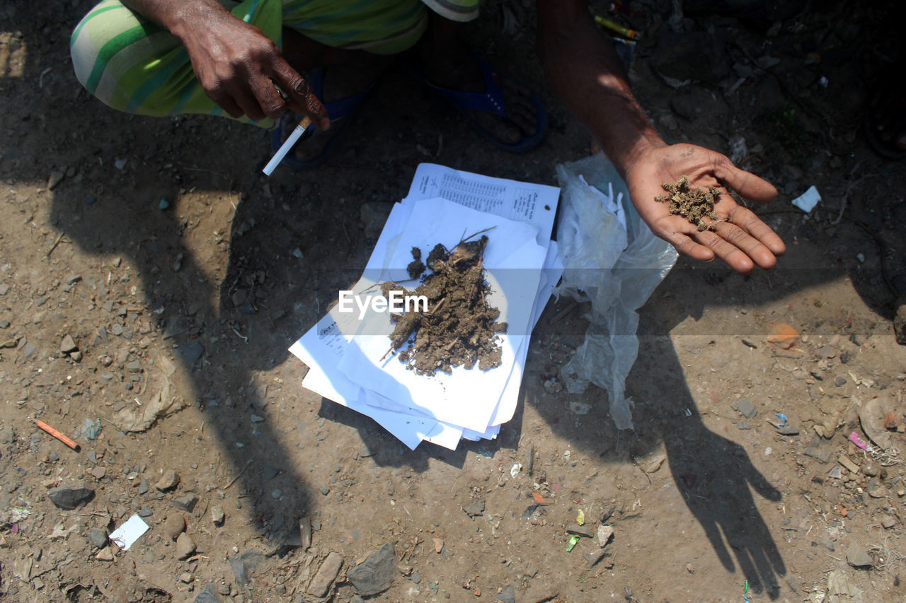 HIGH ANGLE VIEW OF HAND HOLDING PAPER IN FIELD