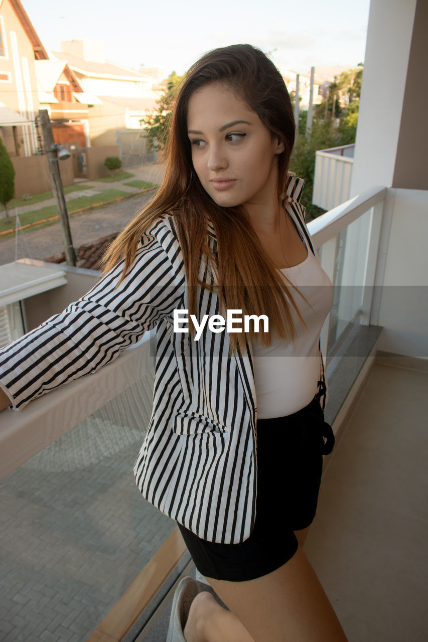 Young woman leaning on railing at balcony