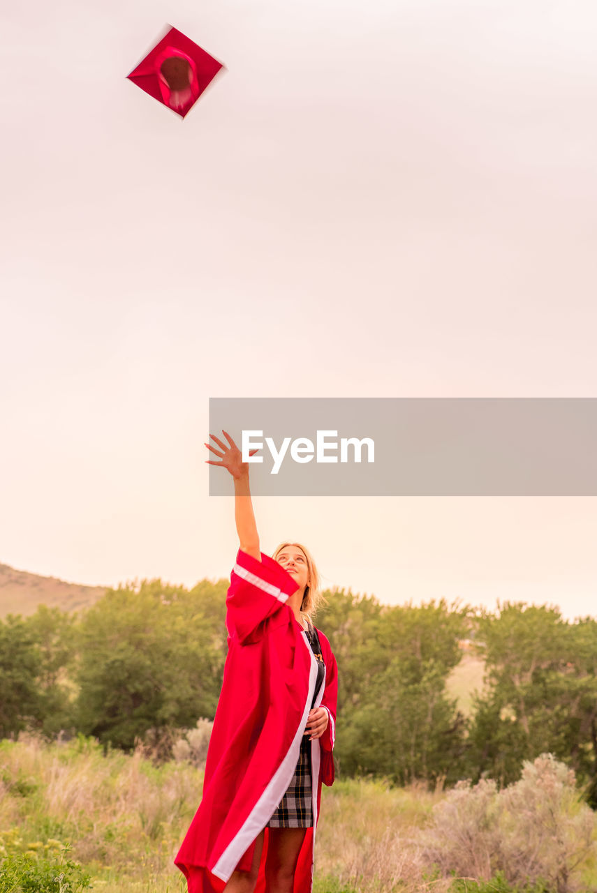 WOMAN STANDING ON FIELD WITH UMBRELLA AGAINST SKY