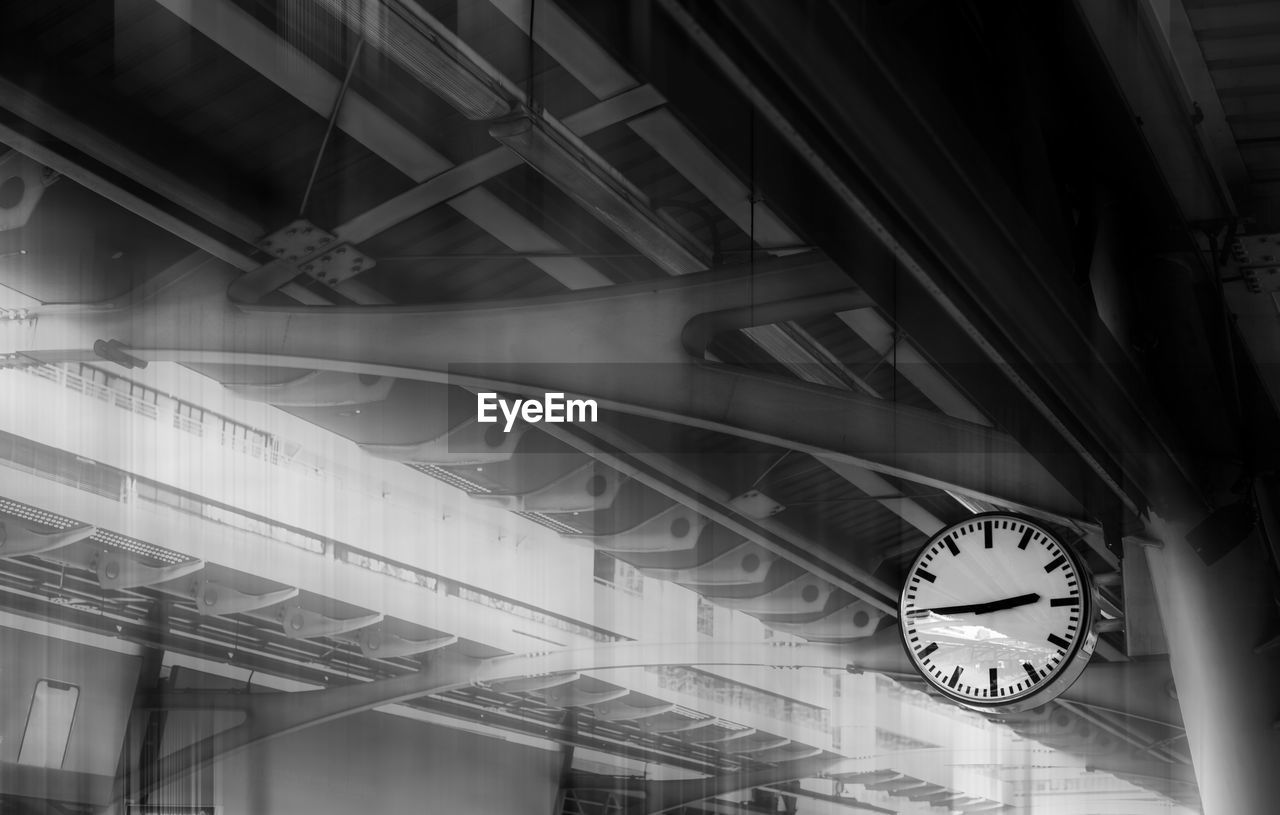 The clock shows the time on the skytrain station with iron structure roof background. 