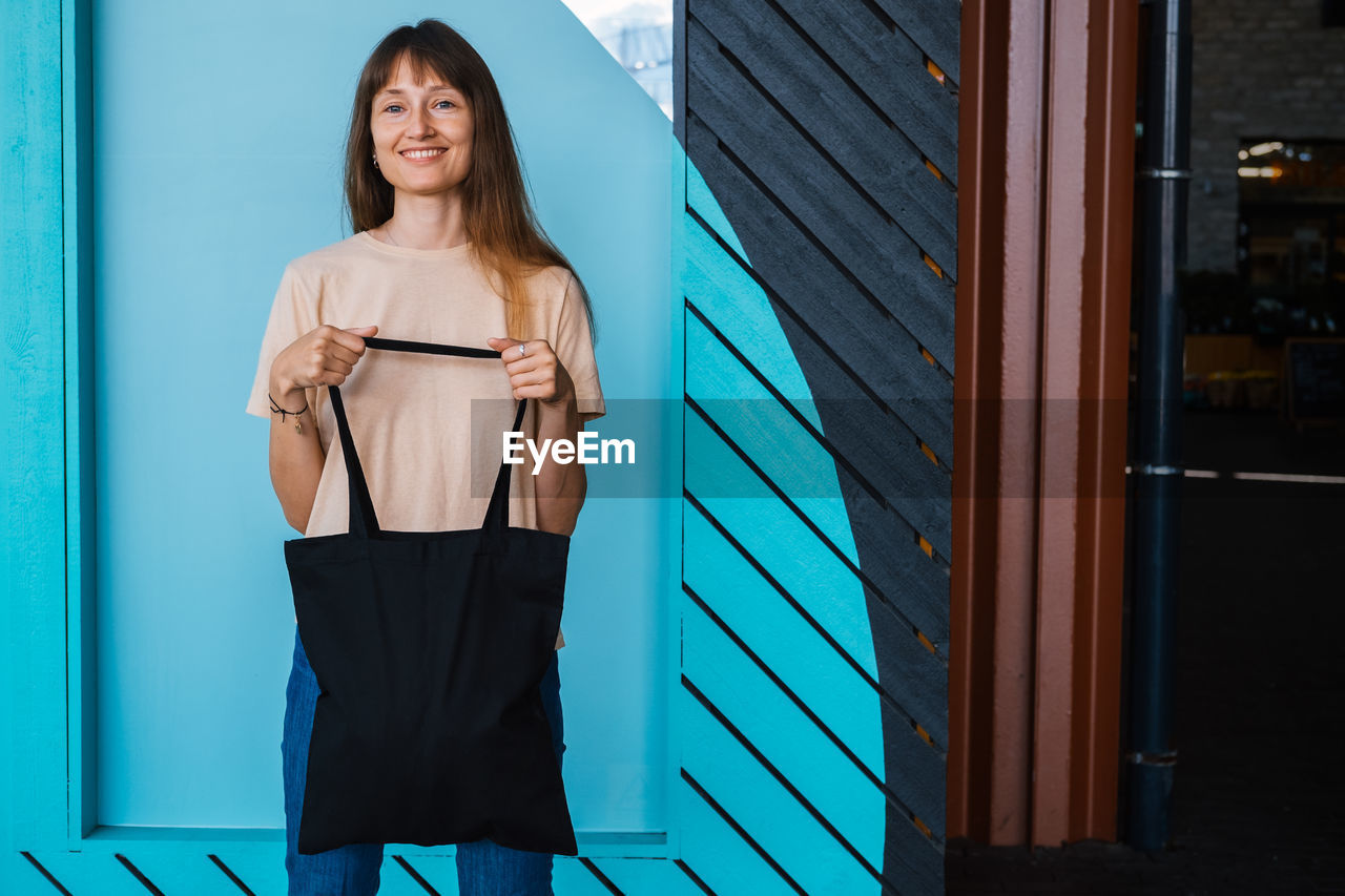 Woman holding black canvas tote bag. bag mockup for design.
