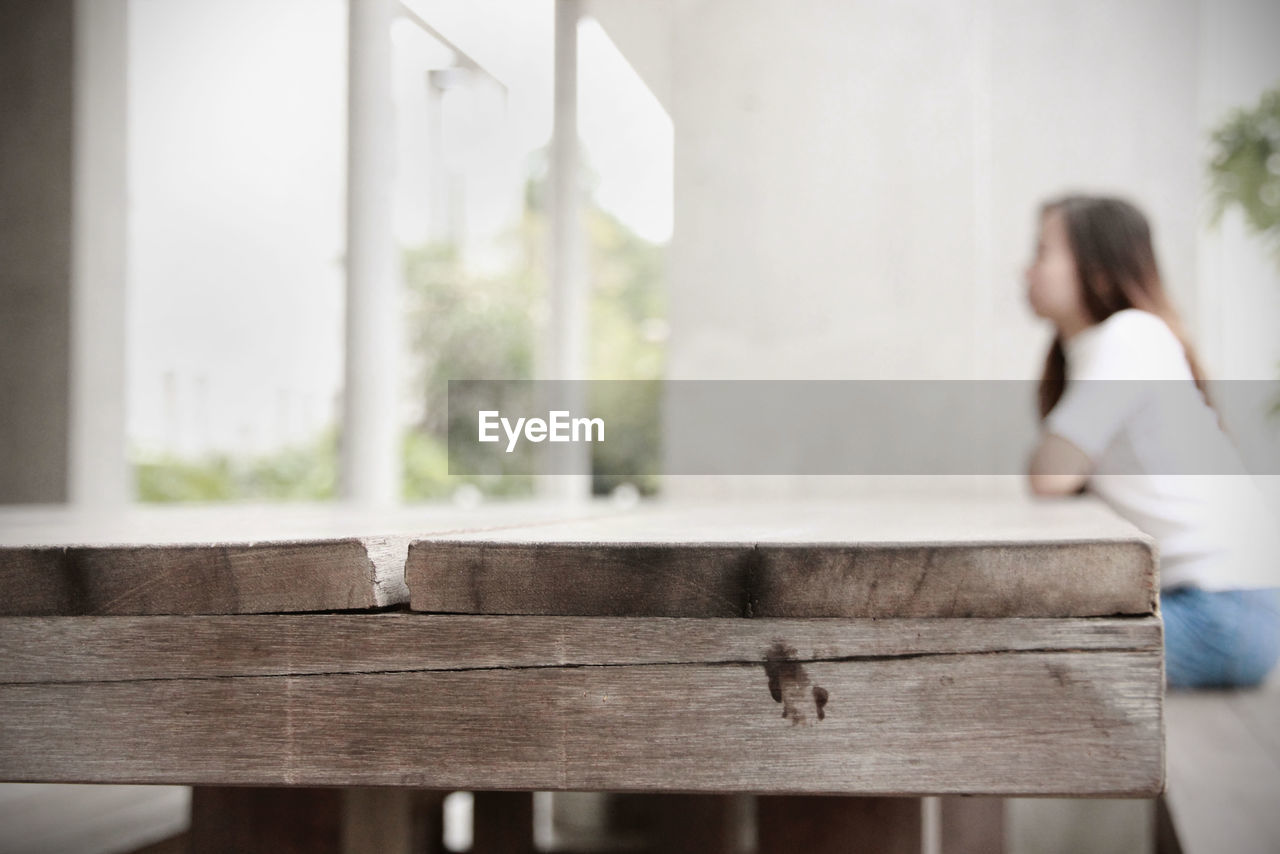 Woman sitting by wooden table at home