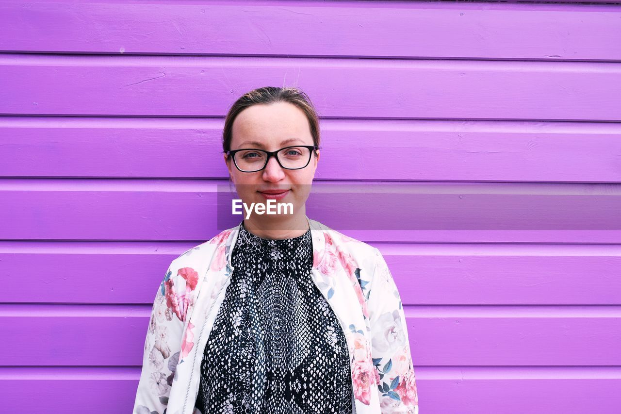 Portrait of woman standing against purple wall