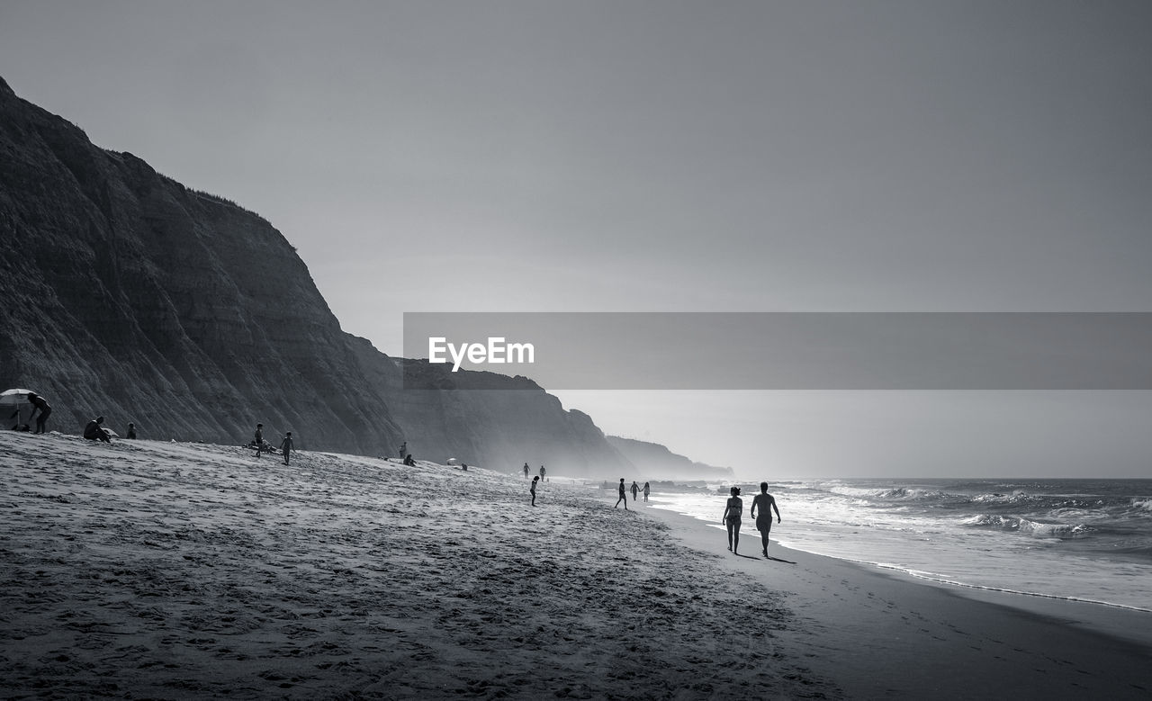 People at beach against sky