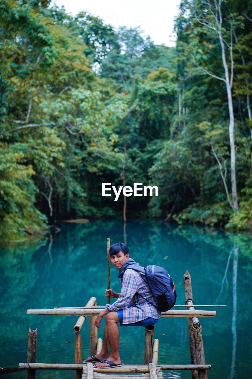 Men sitting in lake against trees in forest