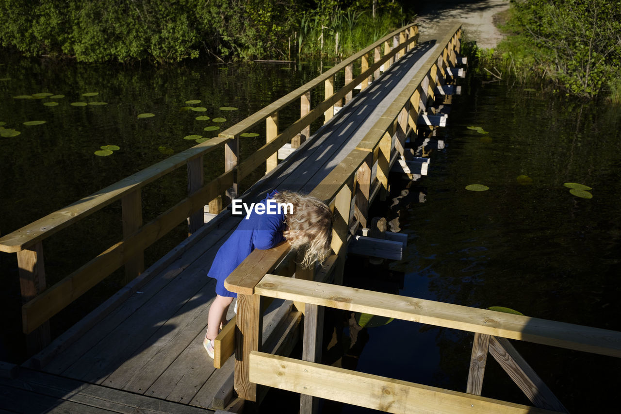 High angle view of toddler on footbridge over lake