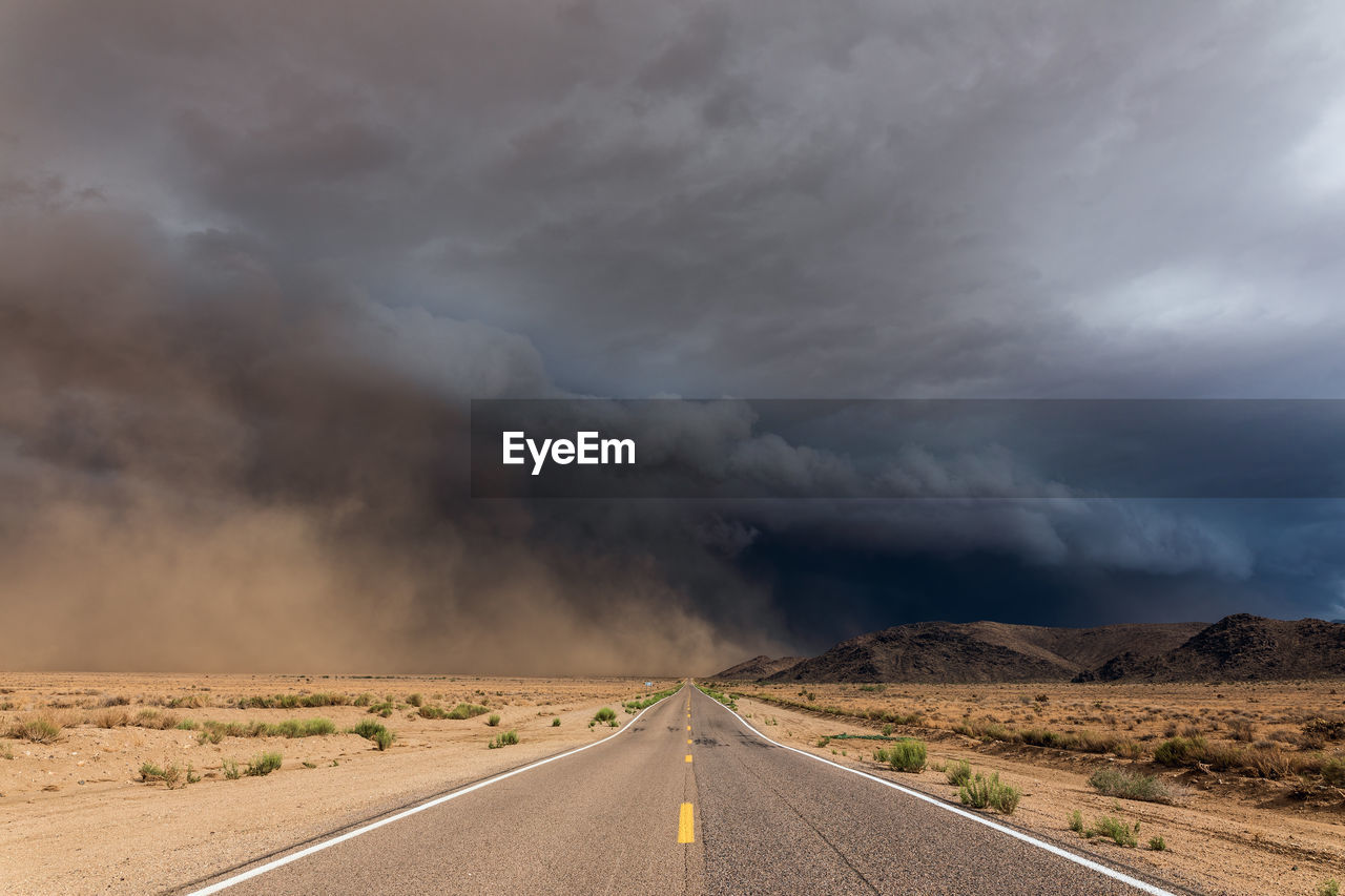 Dark storm clouds and blowing dust approaching a road in the arizona desert.