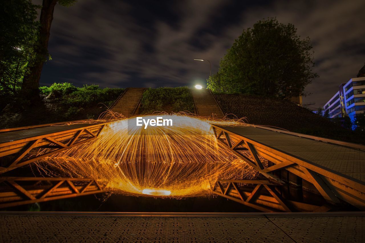 ILLUMINATED TREE BY BUILDING AGAINST SKY