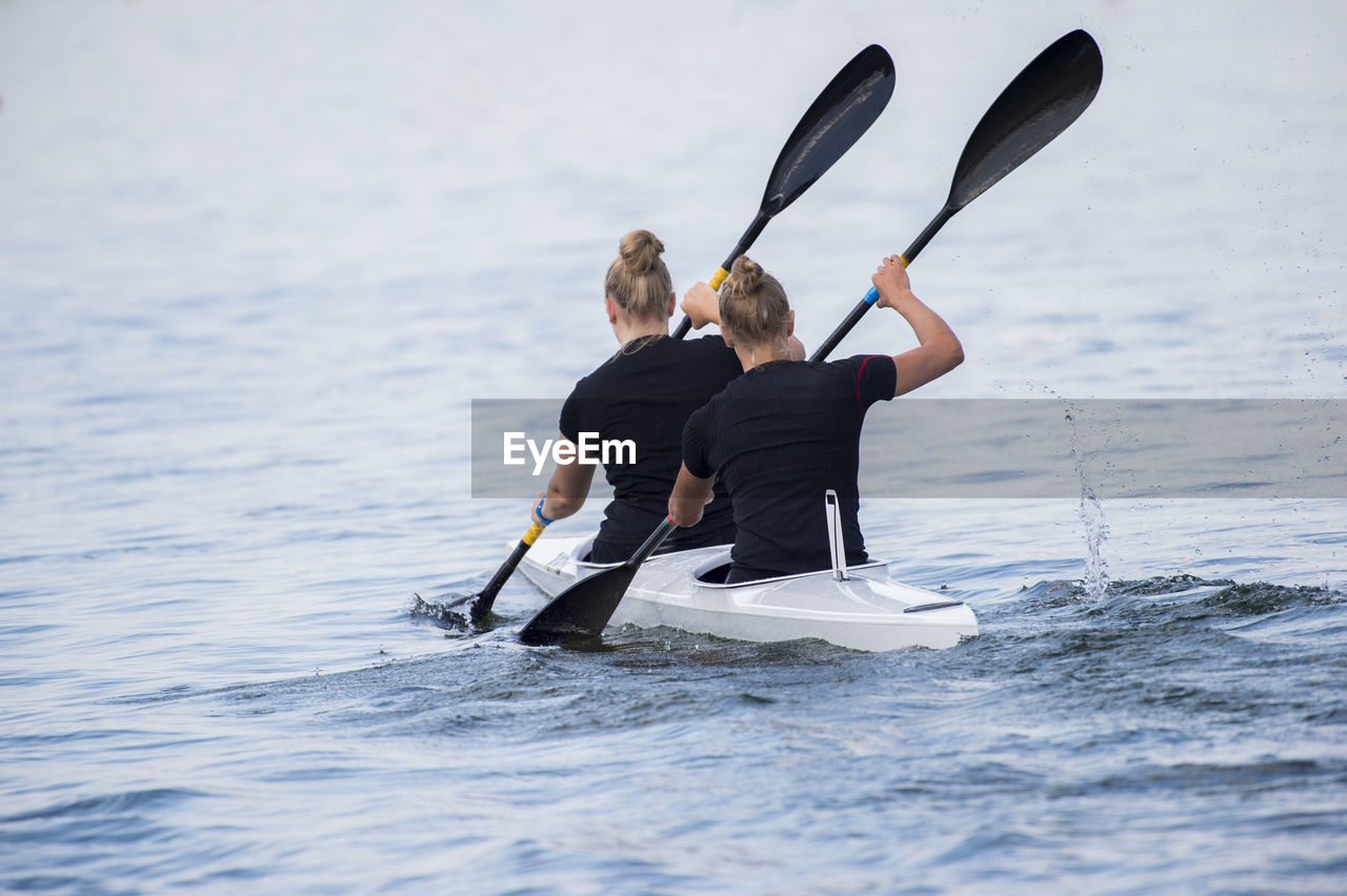 Rear view of female friends canoeing on sea