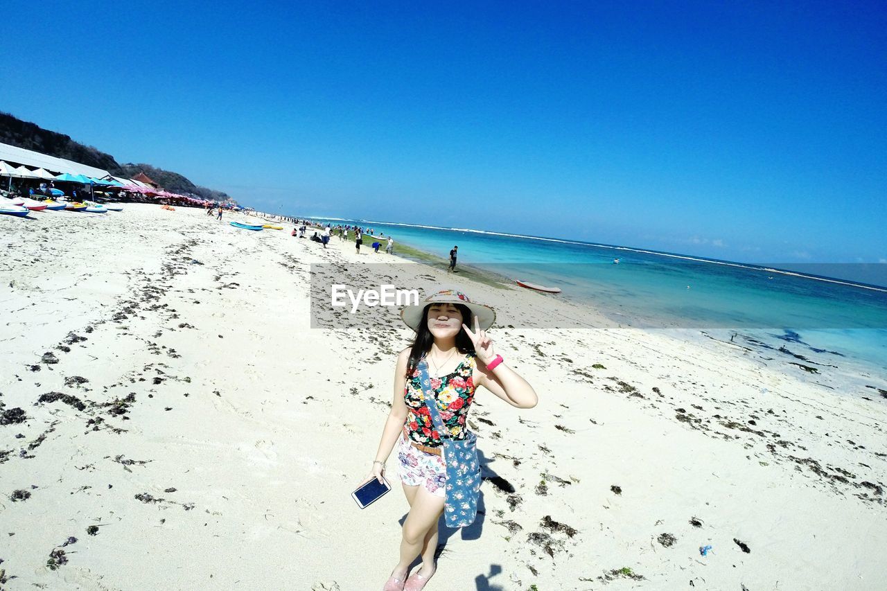 Rear view of woman standing on beach against clear sky