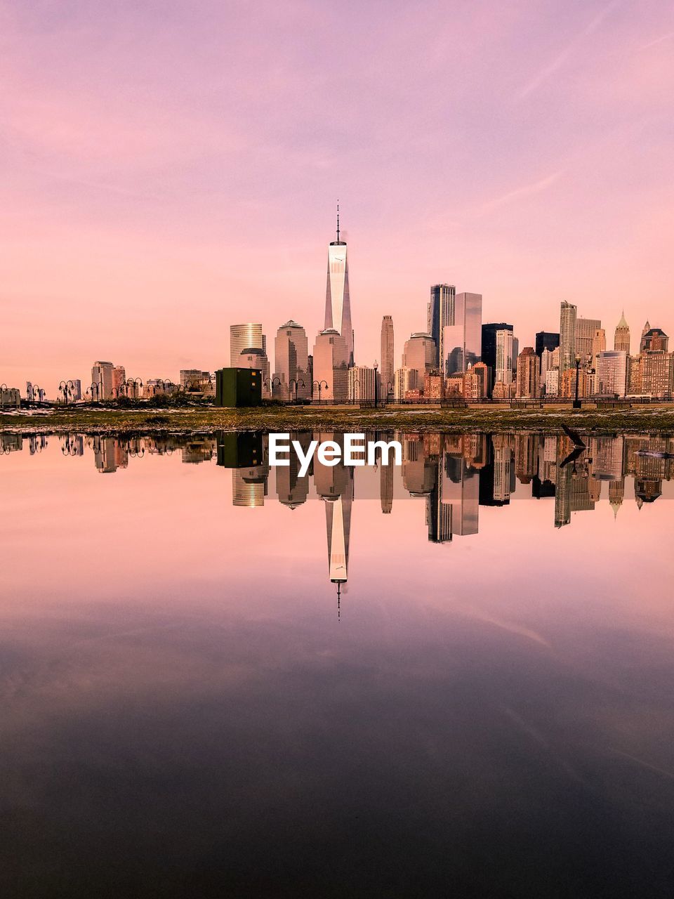 Reflection of buildings in lake against sky during sunset