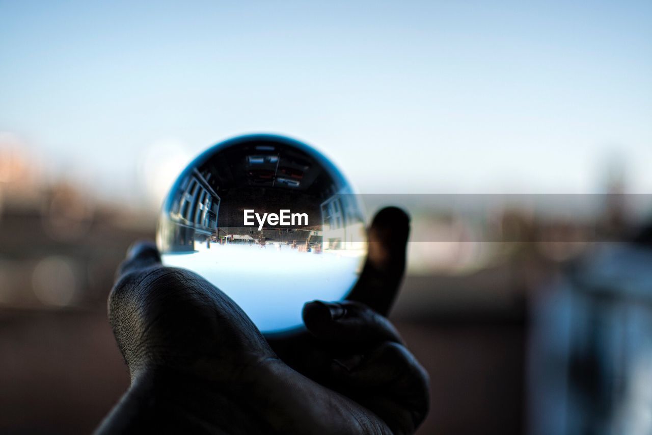 CLOSE-UP OF MAN HAND HOLDING CRYSTAL BALL