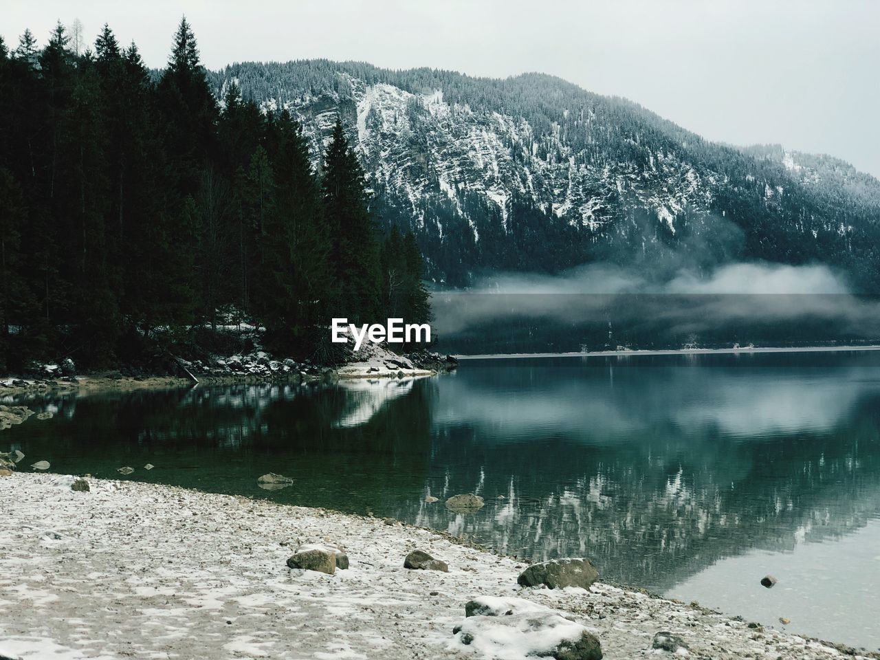 Scenic view of lake by mountains during winter